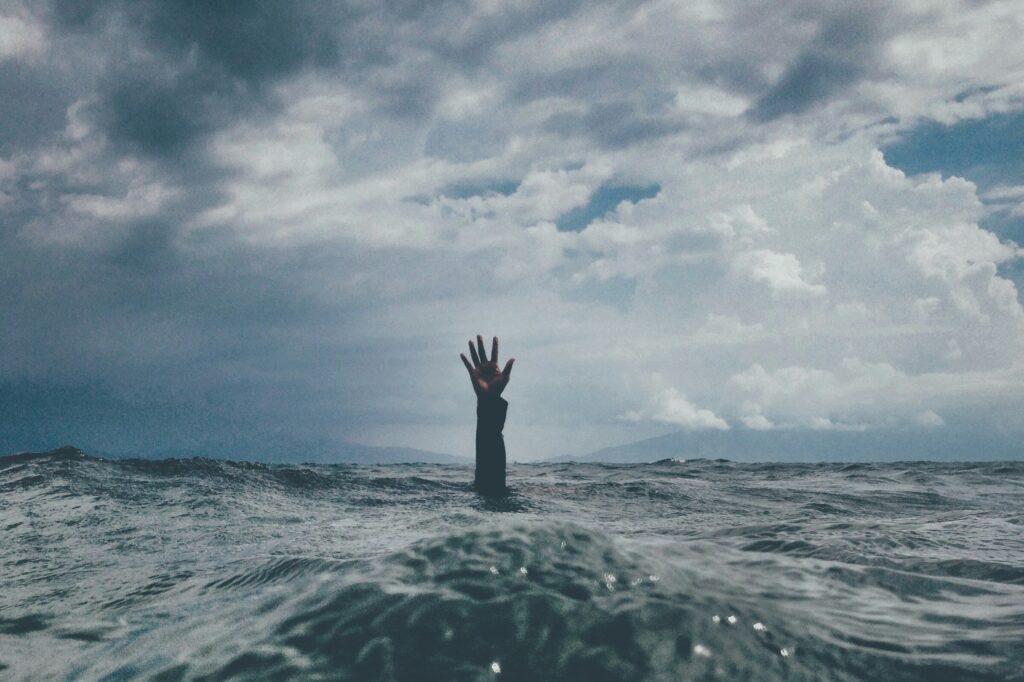 A hand reaching out of the water, symbolizing financial overwhelm and burnout
