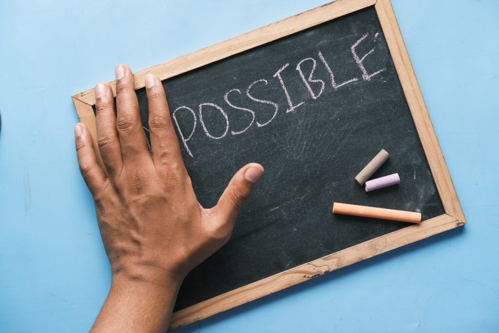 A man’s hand turning the word “impossible” into “possible,” symbolizing a positive financial mindset and new beginnings.